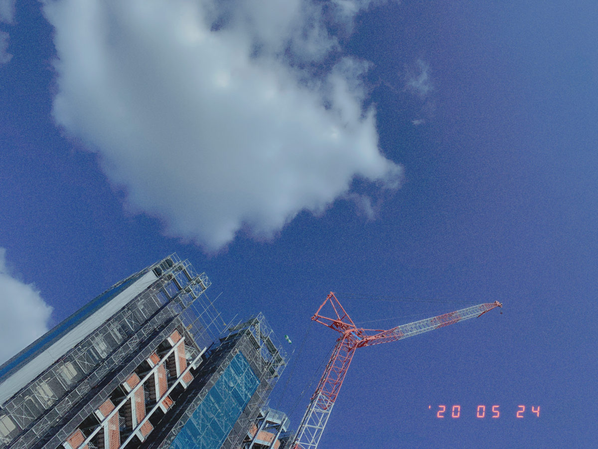 工事中のマンションとクレーンと空の写真