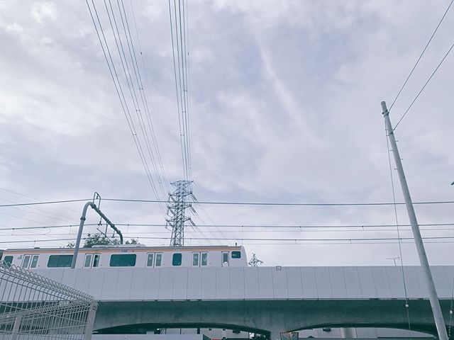 東京を東西に走る中央線の車両の画像。朝の空の下、高架の上を走っている。