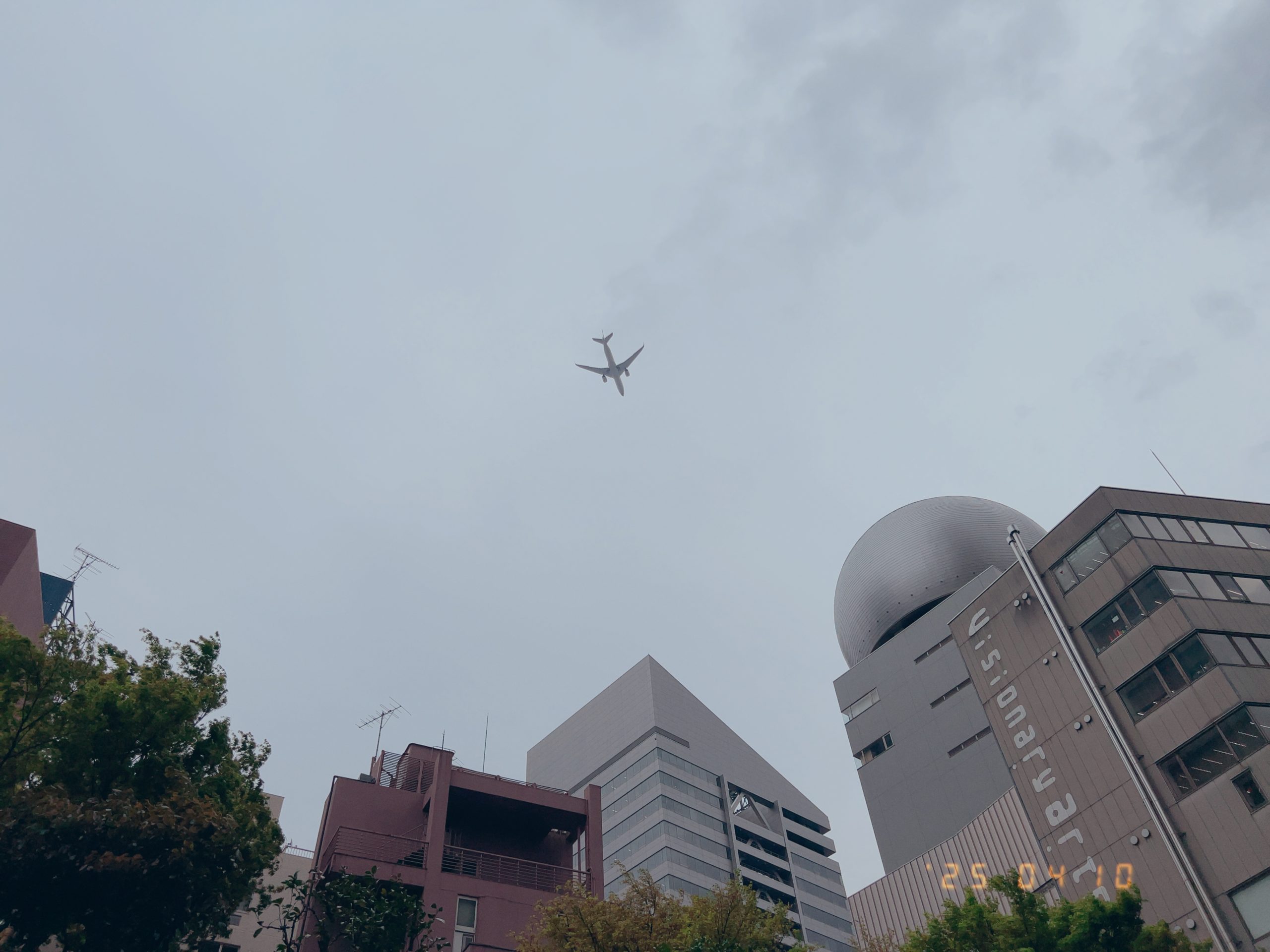 東京都渋谷区上空を飛ぶ飛行機の写真